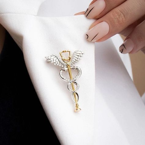 Find a lot more medical pins and nurse brooches in our Shop! https://www.etsy.com/shop/OrbitalEdge These pins are excellent thank you gift for doctors, medical students, nurses, and healthcare professionals. This caduceus brooch featuring a stethoscope is a stylish complement to everyday wear. The pin is available in 2 variants; gold and silver tones. This medical pin is made of plated stainless steel (not an enamel pin) an perfect gift for healthcare workers.  FREE SHIPPING: We offer free shipp Resident Doctor, Doctor Jewelry, Medical Pins, Nurse Jewelry, Medical Quotes, Nursing Pins, Medical Jewelry, Medical School Inspiration, Medical School Essentials