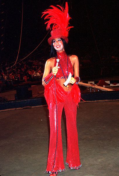 Cher in 1974 dressed as a ringmaster when opening for the Ringling Bros. Circus. This look screams camp style through the excess use of feathers and sequins, and the over-dramatic makeup and accessorizing. (Billboard) Cher Iconic Looks, Cher 1970s, Cher Halloween, Cher Outfit, 70s Cher, Cher Style, Cher 70s, Cher Looks, Cher Costume