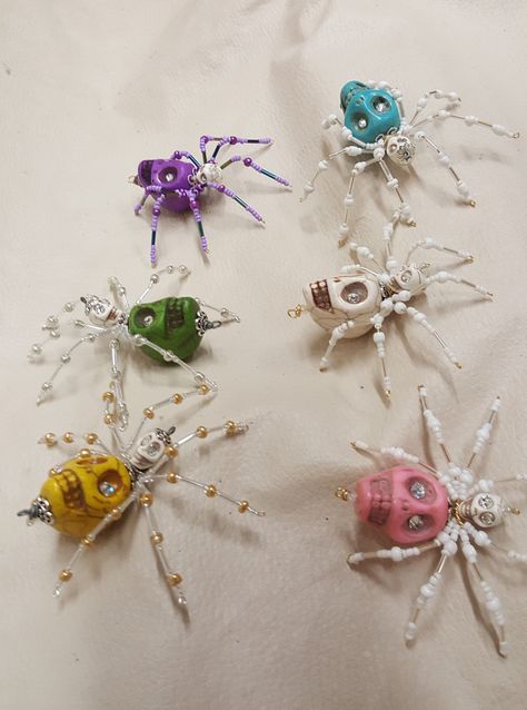 "This is a handmade beaded crystalline spider. The abdominal area is made from a decorative ceramic skull bead which comes in several colors and has jewel encrusted eyes. The head is a smaller white skull bead which also has jewels embedded in the eyes. The legs are made from flexible but sturdy 21 ga. wire which are covered with small glass beads that can be carefully adjusted to almost any position. A gold decorative hook is attached to the back of the abdomen and can be used to hang the spide Ceramic Skull, Christmas Spider, Jewel Encrusted, Seed Bead Crafts, Beaded Spiders, Beaded Crafts, Handmade Wire Jewelry, Beaded Skull, Beaded Animals