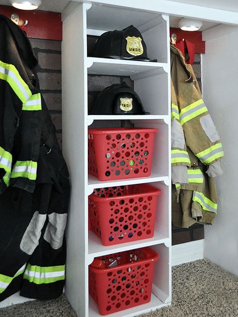 To stow firefighter gear, Corey built a shelving unit from scrap wood and spray-painted inexpensive baskets fire-engine red. Two boards with hooks hold turnout gear./ Firefighter Room Ideas, Fireman Bedroom, Under The Stairs Closet, Fire Truck Toddler Room, Fire Truck Room Decor, Fire Truck Room Ideas Little Boys, Fireman Room, Firefighter Bedroom, Fireman Nursery