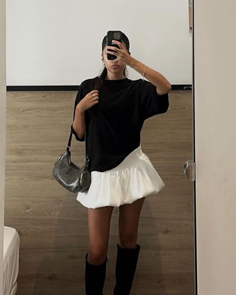 A stylish aesthetic outfit featuring a black oversized t-shirt, a white ruffled mini skirt, black knee-high boots, and a trendy shoulder bag worn by Bianca Barese. Rock Cute Outfits, Mini Black Skirt Fall Outfit, White Ruffle Mini Skirt Outfit, Oversized Tee With Skirt, Oversized Black Tee Outfit, Summer Oversized Outfits, White Ruffle Skirt Outfit, Black And White Skirt Outfit, Mini Black Skirt Outfit