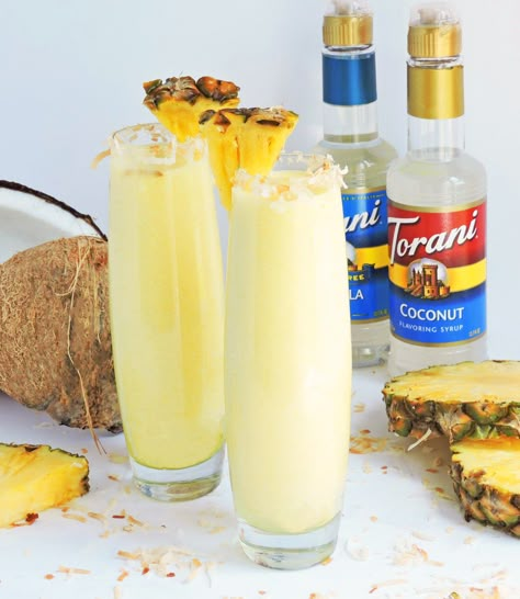 Tropical Pineapple Coconut Cooler served in a tall glass with toasted coconut around the rim, and pineapple wedge-made with Torani Syrups #ad Coconut Syrup Cocktails, Coconut Torani Syrup Recipes, Diy Torani Syrup Recipes, Coconut Syrup Drink Recipes, Blended Pineapple Drinks, Coconut Frozen Drinks, Pineapple Coconut Drink Non Alcoholic, Beverages With Coconut Water, Flavored Coconut Water