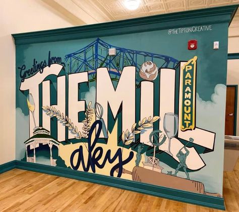 The custom mural by The Tipton Creative, LLC says "Greetings from the Mill AKY". The background is a teal green with mint colored clouds. The mural shows local landmarks, including the Ashland, KY bridges, Central Park gazebo, the Ashland riverfront statues, and the Paramount Arts Center theater sign. Food and drinks like wheat, a cinnamon roll and wine glasses are shown throughout the mural. Postcard Mural, Lincoln Nh, Mural Inspiration, Restaurant Art, Mural Ideas, North Country, Custom Murals, Murals Street Art, Mural Design