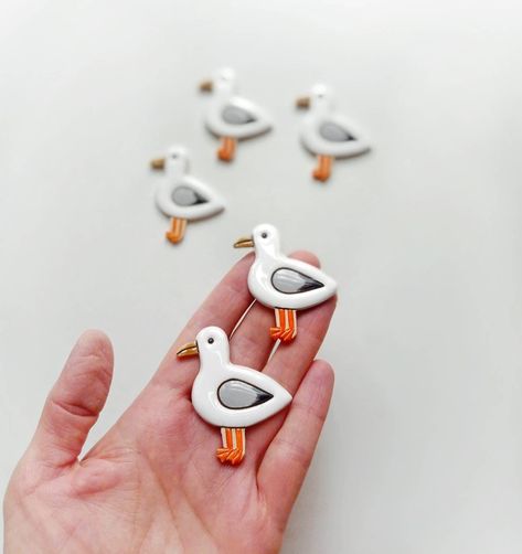 56x42 мм Weight: 8 g  This cute seagull is looking for a friend!  Seagull handmade ceramic brooch.  Made of clay, twice fired at 1050ºC, 1035ºC (with glossy glazes, hand-painted). This brooch is very lightweight. Perfect to wear with a dress, t-shirt, shirt, sweater and coat. There is a pin on the back side. Ceramic Brooches Handmade, Clay Seagull, Ceramic Seagull, Ceramic Pins, Ceramic Brooch, Clay Brooch, Ceramic Magnets, Slab Ceramics, Clay Birds