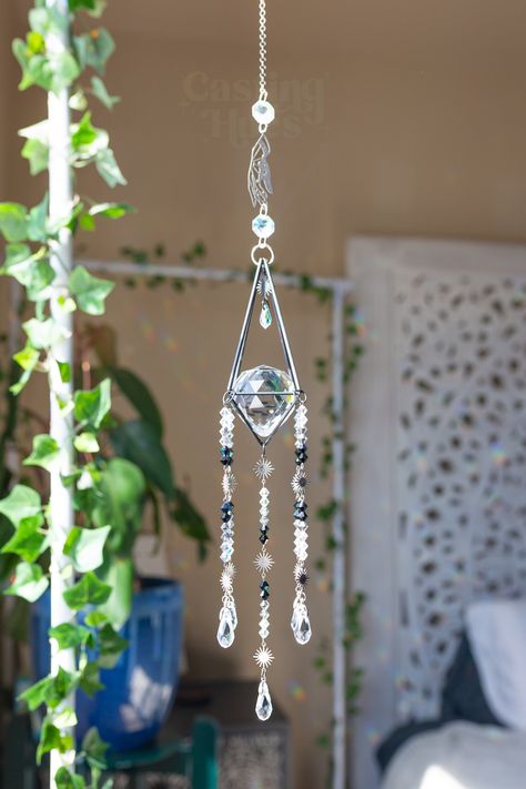 Elevate your space with our stunning Black Whimsical Suncatcher! Handcrafted with high-quality crystals, this enchanting piece captures sunlight, creating mesmerizing patterns and ethereal light displays that add a touch of magic to any room. ✨ What is a Suncatcher? A suncatcher is a decorative item designed to hang in windows, refracting light to fill your space with vibrant colors and unique designs. This gothic crystal suncatcher not only enhances your decor but also promotes positive energy, Refracting Light, Crystal Suncatchers Diy, Unique Window, Diy Suncatchers, Ethereal Light, Window Suncatchers, Hanging Crystal, Crystal Suncatcher, Hanging Crystals