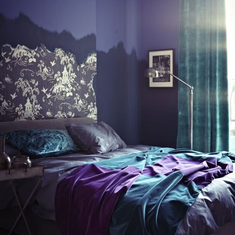 ‘Purple and turquoise?’ you say. Well yes, it really works, and works with ‘wow’! Alone, this dual painted purple bedroom could be dark and eerie, but a panel of turquoise floor-to-ceiling curtains and matching jewel-bright satin bed linen lifts the scheme adding uplifting energy. An artistic ragged-edge, gold chinoiserie wallpaper above the bed makes a decorative and opulent alternative to a headboard. Purple Bedroom Color Scheme, Modern Purple Bedroom, Modern Chic Bedroom, Purple Bedroom Design, Blue Bedroom Colors, Teal Bedroom Decor, Beautiful Bedroom Colors, Design Ložnic, Bedroom Purple