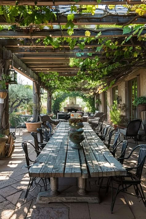 Featuring a wooden dining table, metal chairs, and a pergola covered in climbing vines, this rustic patio is both cozy and charming. The natural materials and greenery create a warm and inviting atmosphere for outdoor dining. Tuscan Patio, Outdoor Covered Patio, Rustic Patio, Outdoor Kitchen Ideas, Covered Pergola, Outdoor Patio Ideas, Pergola Patio, Rustic Outdoor, Outdoor Patio Decor