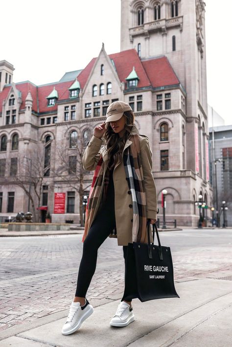 It’s no surprise as to why the trench coat has stood the test of time. The sweeping silhouette is remarkably chic and ideal for combatting the transitional period between winter and spring. Here, I'm wearing my classic Burberry trench coat with a Burberry check scarf and Alexander McQueen oversized sneakers. #burberry #springoutfit #trenchcoat #womensfashion Trench Coat Styling, Coat Styling, Chic Travel Outfit, Outfits Leggins, Looks Adidas, Cute Travel Outfits, Mia Mia Mine, Look Legging, Mia Mia