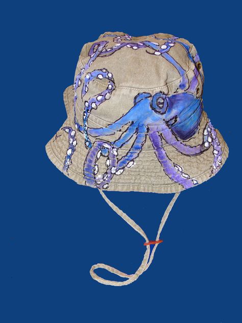 Bucket hat with chin strap has a blue octopus painted all over it. Painted Bucket Hat Ideas, Bucket Hat Painting Ideas, Artistic Hand Painted Beach Hats, Artistic Hand Painted Summer Hats, Painted Bucket Hat, Adjustable Blue Hand Painted Hat, Bucket Hat Painting, Artistic Hand-painted Cap, Diy Bucket Hat