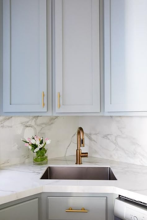 Small gray kitchen with a corner sink and a brass faucet finished with gray cabinets and a marble countertop. Small Gray Kitchen, Corner Kitchen Sink, Corner Sink Kitchen, Kitchen Sink Design, Condo Kitchen, Corner Sink, Gray Kitchen, White Marble Countertops, Kitchen Corner