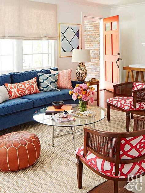 A navy blue sofa establishes this room's complementary color scheme. Bright red appears on the patterned armchair upholstery and on the accent pillows. Shades of tan and brown provide the perfect backdrop for the rich accent colors. Warm Grey Walls, Navy Blue Sofa, Neutral Dining Room, Patterned Armchair, Neutral Furniture, Blue Couches, Living Room Color Schemes, Room Color Schemes, Blue Sofa