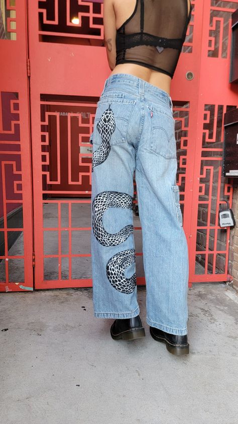 Painted snake pants Snake Jeans Painted, Painted Camo Pants, Painted Denim Jeans Ideas, Paint On Jeans Aesthetic, Diy Pants Paint Aesthetic, Jeans With Painting, Mushroom Jeans Paint, Black Painted Jeans, Painting On Jeans Aesthetic