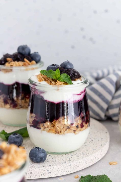 Made with a handful of simple ingredients, this homemade blueberry parfait recipe comes together so quickly and easily! Frozen blueberries cooked down into a delicious sauce and then layered with creamy yogurt and crunchy granola, this blueberry yogurt parfait is perfect to enjoy for breakfast, a snack, or as a dessert. Easy Healthy Yogurt Parfait, Blueberry Yogurt Parfait, Yogurt And Berry Parfait, Blueberry Cheesecake Parfait, Yogurt And Granola Parfait, Blueberry Parfait, Frozen Blueberry Recipes, Breakfast Parfait Recipes, Greek Yogurt And Peanut Butter