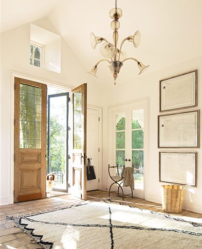 A white painted entryway in Capri Coast OC-87 features vaulted ceilings and a chandelier. Bm Navajo White Walls, Benjamin Moore Navajo White Walls, Bm Linen White Walls, Bm Navajo White, Bm Linen White, Linen White Paint, Backyard Flooring, Painted Entryway, Benjamin Moore Navajo White