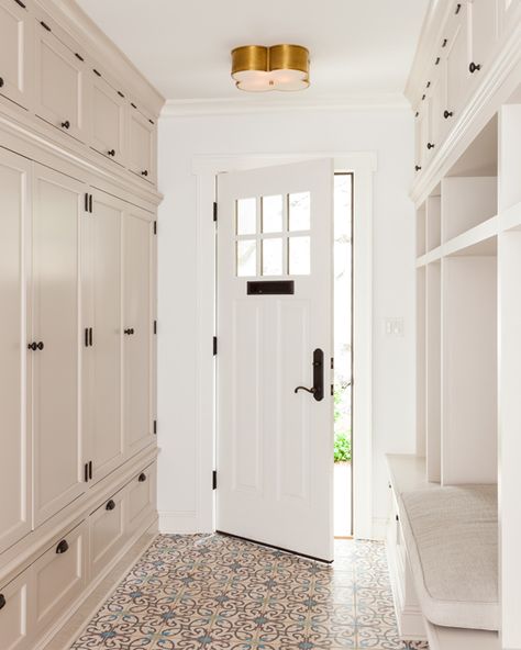 Fabulous long mudroom features a gold clover flush mount, Large Basil Flush Mount, illuminating a wall of floor to ceiling light taupe mudroom locker cabinets adorned with bronze hardware facing a open mudroom lockers and a built in bench with overhead cabinets across from a blue and gray mosaic tiled floor. Entrance Mudroom, Entrance Storage, Mudroom Cabinets, Mudroom Laundry, Laundry Room/mud Room, Mudroom Storage Bench, Side Entrance, Mudroom Lockers, Floor Pattern