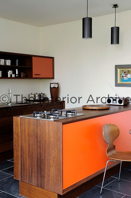 An open-plan kitchen in Scandinavian Modern style in a homely, contemporary space. The wooden kitchen units were handmade in water-resistant iroko with orange laminate on the door fronts and chamfered edges. The orange contrasts beautifully with the Brazilian black slate flooring. Orange And Wood Kitchen, Orange Kitchen Cabinets Black Countertop, Orange Wood Kitchen, Kitchen Interior Orange, 70s Orange Kitchen, Burnt Orange Kitchen, Black Tiles Kitchen, Brick Wall Kitchen, Wood Worktop