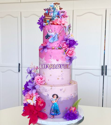 Tall 3 tier cake in shades of pink and purple with Mirabel and Isabela from Encanto covered in fake flowers and sprinkles with the casita on top Buttercream Encanto Cake, Isabela Cake Encanto, Encanto Cake Simple, Isabela Encanto Cake, Isabella Encanto Cake, Encanto Treats, Cake Pink And Purple, 3 Tier Birthday Cake, Tier Birthday Cake