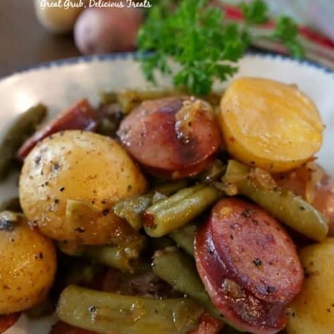 Preheat oven to 400° and spray a 9x13 baking dish with a non stick spray. Wash creamer potatoes, cut in half and add to a sealable gallon size baggie. Add oil, seasonings, pepper and red pepper flakes to baggie. Shake to coat. In a large frying pan, add sausage and water and cook over medium high heat until sausages have browned and most of water has evaporated. Remove sausage from pan and when cool enough add to baggie. Melt butter in frying pan and add onions and garlic, cook until onions ... Sausage Green Bean Potato Casserole, Green Bean Potato Casserole, Sausage Green Beans, Sausage And Green Beans, Sausage And Potato Bake, Green Beans Side Dish, Beans And Potatoes, Potatoes Green Beans, Potatoes And Green Beans