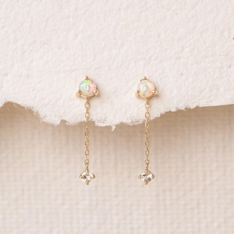 Iridescent opal stud earrings with a 14k yellow gold dangle chain and a dainty white topaz stone. Made in 14k solid gold. The opal gemstones measure at 3mm with a chain length of 10mm. Opal Dangle Earrings, Pretty Earrings Aesthetic, Gold Opal Earrings, Opal Earrings Dangle, Opal Jewelry Earrings, Church Girl, Wardrobe Building, Peach Jewelry, Gold Chain Earrings