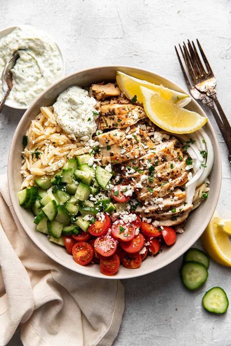 These greek chicken orzo bowls are filled with orzo pasta, seasoned chicken breast, english cucumbers, cherry tomatoes, homemade tzatziki and feta cheese. A healthy but easy to make dinner the whole family will enjoy. The perfect summer evening dinner. Greek Chicken Bowls With Tahini Feta Sauce, Greek Tahini Chicken And Feta Orzo Bowls, Chicken Orzo Bowl, Orzo Bowls, Orzo Bowl, Greek Chicken Orzo, Greek Bowls, Greek Bowl, Mediterranean Chicken Bowl