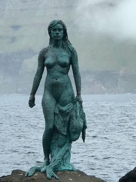 While on the island of Kalsoy, a visit to the village of Mikladalur (population 44) is a must - to see the selkie-statue - Kópakonan. The legend of Kópakonan is one of the best known folk-tales on the Faroe Islands. Selkie Statue, The Twelfth Night, Christian Festival, Woman Statue, Old Post Office, Water Spirit, Sculpture Projects, Faroe Islands, On The Rocks