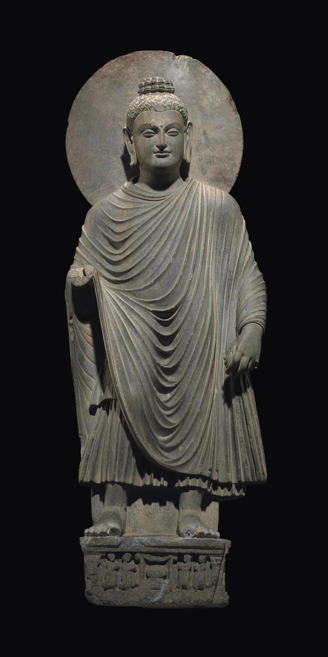 A large gray schist figure of a standing Buddha  Gandhara, 2nd/3rd century  Superbly carved standing on a plinth with worshippers flanking a stupa, wearing voluminous robes with cascading folds, his left hand lowered, his face in a benevolent expression with crisply delineated features and elongated earlobes, his hair arranged in fine locks rising over the ushnisha, his face backed by a smooth nimbus 45½ in. (115.6 cm.) high Asian Art Reference, Gandhara Buddha, Gandhara Art, Pursuit Of Knowledge, Standing Buddha, Buddha Garden, Mahayana Buddhism, South Asian Art, Indian Sculpture