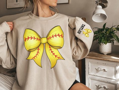 Show off your softball pride with our custom Softball Sweatshirt featuring a Coquette Bow! 🥎🎀 This stylish and cozy sweatshirt is perfect for every softball lover. Featuring a charming softball coquette bow on the front and the option to personalize the sleeve with any text, it's a perfect way to celebrate your love for the game and your favorite player. 🌟 Adorable Softball Coquette Bow Design: This sweatshirt features a beautifully detailed softball coquette bow on the front, combining sport Softball Sweatshirt Ideas, Softball Games, Softball Sweatshirt, Softball Shirt Designs, Softball Mom Shirts, Custom Softball, Etsy Clothes, Casual Preppy Outfits, Softball Mom