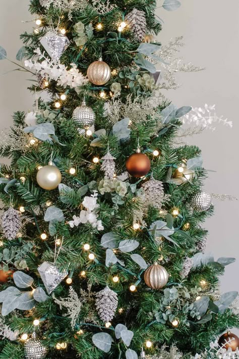 Eucalyptus stems, glitter branches, frosted pinecones, and metallic ornaments help create this simple rustic Christmas tree! Farmhouse Christmas Diy, Frosted Pinecones, Metallic Ornaments, Eucalyptus Stems, Blue Christmas Decor, Simple Tree, Alternative Christmas, Farmhouse Christmas Tree, Alternative Christmas Tree