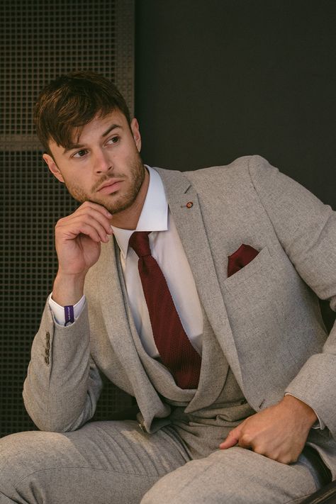 Male model sitting in a three piece light grey tweed suit withA burgundy tie and pocket square combined with a crisp white shirt. Clicks through to grey suits on Slater Menswear site. Groom Suit Colors Wedding Ideas, Light Grey Tweed Suit, Charcoal Grey Suit Wedding, Men's Grey Suits, Summer Groomsmen, Light Grey Suit Men, Charcoal Suits, Skye Costume, Turtleneck Suit