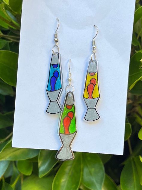 These super cute earrings are lava lamps made out of shrinky dinks. They come in 3 different color options. They are lightweight and perfect for any fun outfit! Lava Lamp Earrings, Shrink Plastic Ideas Diy, Shrinks Dink Ideas, Rhinestoned Things, Cute Shrinky Dink Ideas, Shrinky Dink Ideas Templates, Juniper Art, Shrink Earrings, Woodstock Theme