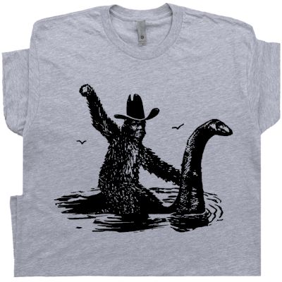 Bigfoot T Shirt | Sasquatch Riding Loch Ness Monster | Cryptozoology T Shirt Sasquatch Shirt, Bigfoot Humor, Monster Tshirt, Loch Ness Monster, Funny Shirts For Men, Loch Ness, Bold Logo, Novelty Shirts, Funny T Shirts