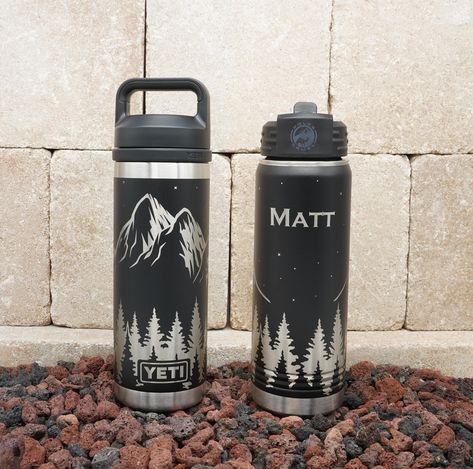 "Perfect for camping or hiking, this beautiful outdoor scene features majestic mountain peaks above a lush line of trees underneath a night sky with twinkling stars!  Can you smell the fresh pine?  ;-) Available on YETI® water bottles in 26oz & 18oz capacity in black.  Also available on Polar Camel water bottles in 32oz & 20oz capacity, with your choice of 16 colors.  This item may be purchased with or without personalization.  Names will be added on the opposite side of the water bottle from th Water Bottle Engraving Ideas, Yeti Engraving, Engraved Water Bottles, Yeti Cup Designs, Engraved Yeti, Trendy Water Bottles, Water Bottle Brands, Engraved Tumblers, Engraving Ideas