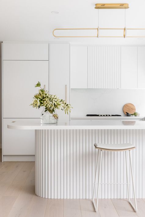 White Kitchen Cabinets with Gold Lighting Fixture This all-white kitchen is enhanced with gold accents and wood panels. Flat White Kitchen Cabinets, Minimalist Kitchen Ideas, Gold Lighting, White Kitchen Island, Kitchen Island Table, Island Bench, Minimalist Kitchen Design, Flat Panel Cabinets, Black Kitchen Cabinets