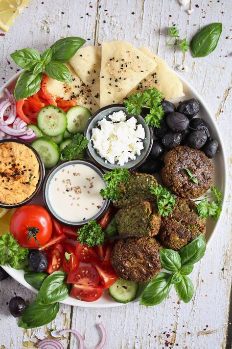 A beautiful falafel plate with homemade hummus and falafel, vegetables, olives, feta, tahini sauce, and bread. Delicious and easy to pull together mezze platter to satisfy your Middle Eastern food cravings. #thefastrecipe #falafelplate #falafelplatter #falafelmezzeplatter #falafelmezzeplate #mezzeplate #mezzeplatter Creamy Hummus Recipe, Mezze Platter, How To Make Falafel, Vegan Plate, Middle Eastern Food, Mini Bundt, Bacon Wrapped Asparagus, Homemade Hummus, Tahini Sauce