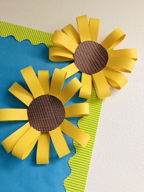 Love these little details!   Supplies needed: construction paper, scissors, ruler, permanent marker, stapler, hot glue.     •Create petals by using construction paper and ruler.  •Cut, bend, and staple together to make flower.   •Use ruler to make lines for the middle of your sunflower  •Glue middle to your flower.   •Attach to board/door or wherever your choose! Flowers For Bulletin Board Diy, Construction Paper Classroom Decor, Construction Paper Sunflower, Sunflower Door Decor Classroom, Fall Construction Paper Crafts, Sunflower Bulletin Board Ideas, Chart Paper Decoration Ideas, Sunflower Crafts For Kids, Sunflower Classroom Decor