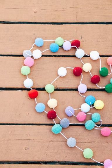 Here's a super easy and inexpensive way to add some colorful and whimsical decor to your kids rooms. Start with some colorful pom poms, a blunt needle and some twine or string. I used cute pink and white baker's twine. Aren't these colors the best?? :) String your thread or twine through the needle. Then simple "sew" through each pom pom. Here's a closeup! These pom poms are not difficult to sew through at all. This project goes very fast, actually! Here's a quick tip… Diy Pom Pom Garland, Pom Pom Necklace, Rainbow Garland, Diy Pom Pom, How To Make A Pom Pom, Pom Garland, Lamb Decorations, Rainbow Room, Pom Pom Garland