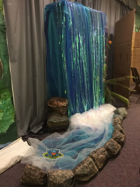 Side view of stage waterfall feature. Glittered, colored tulle made for look with shiny tinsel (actually a backdrop for a Photo Booth...found at Walmart). Lined with paper rocks. Fake Waterfall, Cave Quest Vbs, Waterfall Decoration, Waterfall Backdrop, Diy Waterfall, Jungle Decorations, Vbs Themes, Waterfall Features, Backdrop Wedding