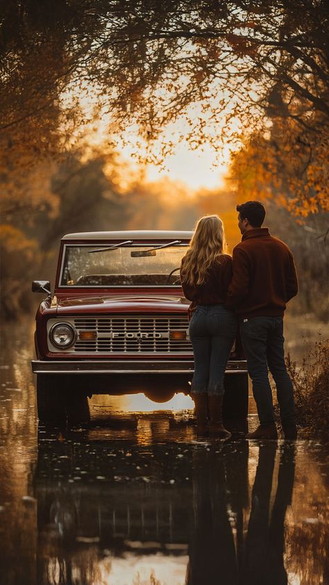 A couple stands together in front of a vintage red Ford truck, surrounded by warm autumn colors and reflections on a calm water surface. The scene captures a romantic and nostalgic fall atmosphere, perfect for outdoor photography and cozy moments. Old Car Family Photoshoot, Couples Photoshoot Vintage Romantic, Engagement Truck Photos, Winter Truck Photoshoot, Photos With Old Truck, Truck Pictures Ideas, Cute Fall Couple Pictures Photo Ideas, Couples Truck Photoshoot, Truck Couple Photoshoot