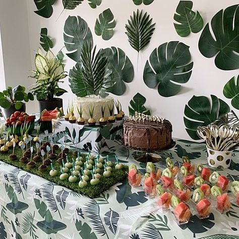 Create a tropical themed party ambiance and set up an enticing dessert station. Dress up the table in a tropical leaf print tablecloth and give your desserts a unique look by presentation them on a grass rug. Choose clear dessert cups, black cake stands, & cake riser to showcase the tempting treats and put gold cutlery in a polka dot cup. Create an authentic tropical feel by using palm leaves as cake topper and decorate the wall with Monstera leaves to add color and texture to your party decor. Tropical Dessert Table, Tropical Birthday Theme, Brazil Party, Palm Springs Pool Party, Brazilian Sweets, White Dessert Tables, Tropical Wedding Reception, 21st Birthday Themes, Event Decor Ideas