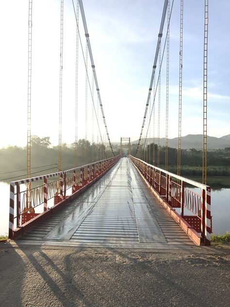 Kon Klor suspension bridge is located in Kon Klor village, Kon Tum town, is the most beautiful industrial suspension bridge in the Central Highlands region. The bridge is 292m long, 4.5m wide, built on February 3, 1993 and inaugurated on May 1, 1994, with a striking orange color. The Dak Bla River in the dry season paves out pebbles by the smooth, harmonious riverbed, the shadow of a majestic bridge printed under the calm water.  #KonKlor_Brigde  #KonTum #Vietnam Travel #BrigdeinVietnam Kon Tum, Suspension Bridge, February 3, Calm Water, The Calm, Vietnam Travel, The Shadow, The Bridge, May 1