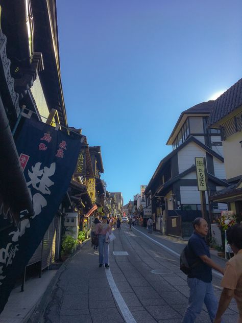 Photo taken during the afternoon looking up a Japanese street lined with buildings either side. Many of the buildings have a traditional (I believe Edo era) Japanese appearance and have banners at the front. There are people walking along the side of the road and in front of the shops. A few cars can be seen on the road in the distance. Chiba Japan, Japan Life, Narita, Japan Aesthetic, Aesthetic Pics, Chiba, Red Fire, Where The Heart Is, Tokyo Japan