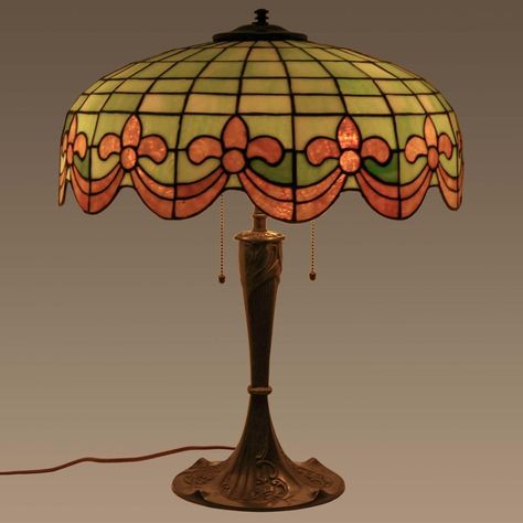 Antique American bronze and leaded glass table lamp by Wilkinson, circa 1910. The three light lamp having a dome shaped shade with striated leaded glass green & ivory tiles and having amber colored Fleur-de-Lis & swagged garland decoration to the base of the shade. The lamp is raised on the original bronze base decorated in an organic Art Nouveau design. The lamp is in very good condition and has been sympathetically rewired with period style materials, creates a warm pleasant light.  Bloomsbury Tiffany Lamp Vintage, Vintage Touch Lamp, Lampe Art Nouveau, 1920s Lamp, Fancy Lamp, Art Nouveau Lamp, Eclectic Lamps, 1920s Decor, Tiffany Lamp Shade