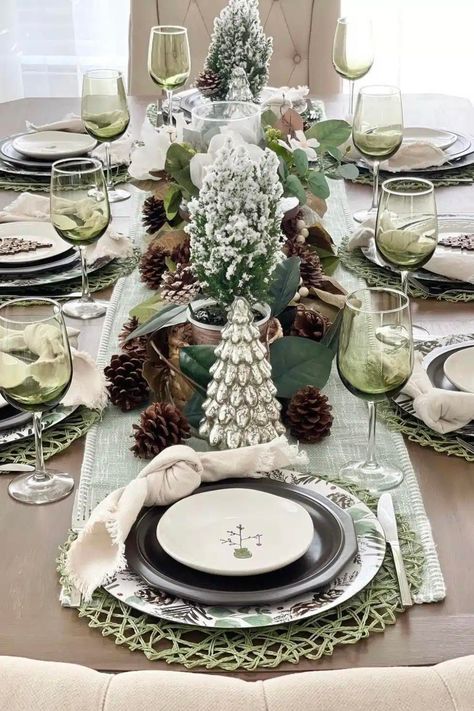 Elegantly set Christmas dining table with green placemats, white plates, bow-tied napkins, and a festive centerpiece. Green wine glasses complete the joyful setting, offering fun and search-worthy Christmas table decor ideas and interior inspiration." Evergreen Christmas Table Decor, Green Xmas Table Setting, Green Placemats Table Setting, Christmas Tree Dining Table Decor, Sage Green Christmas Table, Green Table Set Up, Green Christmas Table Settings, White And Green Table Decor, Christmas Dinner Table Settings Rustic