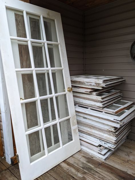 Old windows and doors that will be used to make a greenhouse. Small Greenhouse Old Windows, French Door Greenhouse, Old Window Greenhouse Diy Recycled Door, Greenhouse Using Old Windows, Greenhouse Door, Window Green House, Greenhouse Old Windows, Greenhouse Made From Old Windows, Window Greenhouse Diy