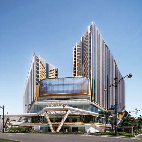 The façade of the podium is a dynamic composition of fluid white forms, providing a striking contrast to the functional rectangular form of the building. Gold and white canopies, that wrap the podium, provide a sense of movement and energy, accentuating the entrances of the arena, exhibition space, and hotel. The façade is further enhanced by integrated, programmable LED lighting and large-scale screens, which enliven the architecture and create a distinctive new presence on the Macau skyline. Convention Center Design, Urban Living Room, Macau China, Green Terrace, Architecture Practice, International Architecture, White Canopy, The Two Towers, Entertainment Design