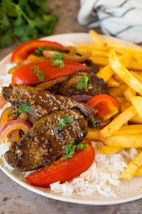 This lomo saltado is a classic Peruvian dish of tender beef that's stir fried with tomatoes and onions in a savory sauce, then served with french fries and steamed rice. Lomo Saltado Recipe Peruvian, Lomo Saltado Recipe, Spanish Foods, Peruvian Dishes, South American Recipes, Lomo Saltado, Cuban Cuisine, Peruvian Cuisine, Frozen French Fries