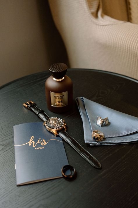 a grooms vows, watch, vanilla+tobacco cologne, wedding band and cufflinks sit on a dark wood table side a blue-grey pocket square. Wedding Details Photography Groom, Men’s Getting Ready Wedding, Groom Flatlay, Groom Detail Shots, Wedding Band Tattoos, Grooms Details, Wedding Accessories Photography, His Wedding Band, Glacier Elopement