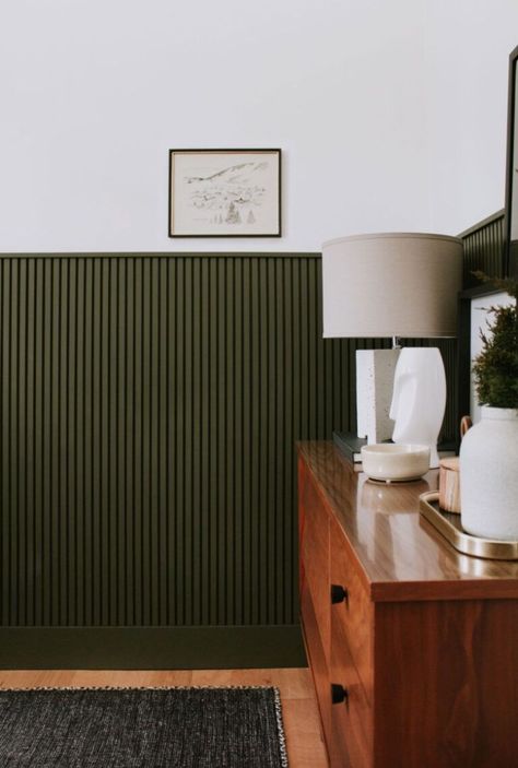 The once popular “retro 70’s style” wood panel accent wall is making a comeback in a bIG way! now considered mid century modern slat wall, DIY’ers everywhere are slatting all. the. spaces! we’ve rounded up accent walls both indoor and out if you’re on the hunt to add a slat accent wall to your own... Office Wainscoting, Wood Panel Accent Wall, Green Wainscoting, Modern Slat Wall, Panel Accent Wall, Slat Wall Diy, Slat Accent Wall, Nadine Stay, Slat Walls