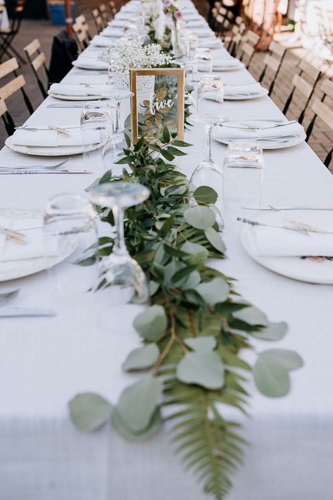 This simple long table wedding reception features mixed greenery and babys breath decor, glass table numbering, and wooden chairs by Kim Jay Weddings Long Table Wedding Decor, Long Table Wedding Reception, Simple Wedding Tablescapes, Long Table Decor, Table Numbering, Long Table Decorations, Long Table Centerpieces, Table Wedding Decor, Long Table Wedding