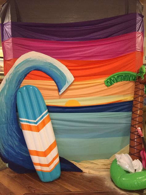 Sunset background for beach theme party! Layered plastic tablecloth for sunset effect and painted wave out of 70 in tv cardboard. Surfboard float and palm inflatable top it off! #sunset #diycrafts #diyparty #diyparty decor #diypartydecorations #diypartyplanning Sunset Beach Party Decorations, Sunset Backdrop Diy, Sunset Backdrop Party, Indoor Beach Party Decorations, Beach Theme Decorations Party, Diy Surfboard Decor Party, Cardboard Surfboard, Diy Beach Birthday Decor, Diy Surfboard Decor Cardboard